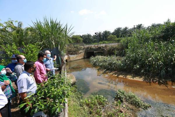 Ka Siong (kanan) meninjau saliran berhampiran landasan kereta api yang menyebabkan banjir di Kampung Baru Slim River. 