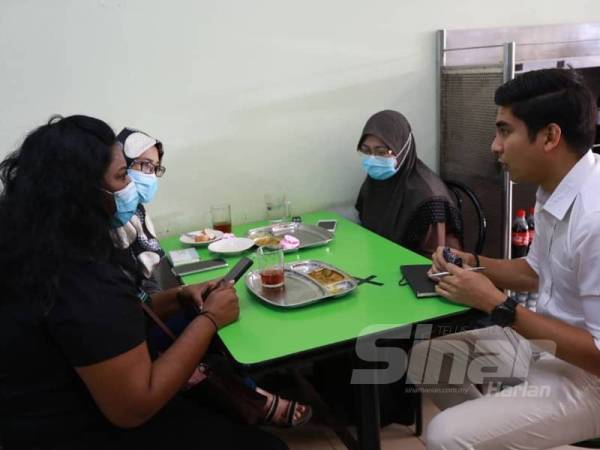 Syed Saddiq (kanan) mendengar luahan anak muda pada program sarapan bersama rakyat di Sungkai hari ini.