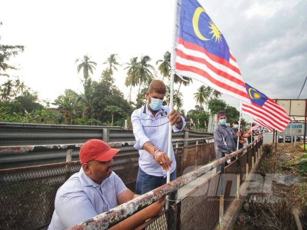 Jasvir Singh (dua dari kiri) memasang Jalur Gemilang di Kampung Ketari, Bentong baru-baru ini. 