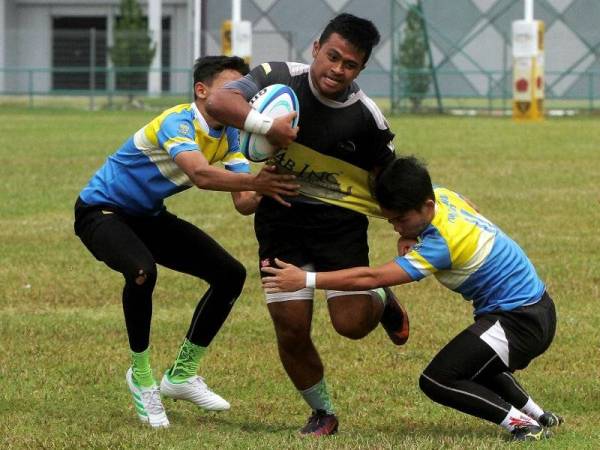 Pemain Perak, Muhammad Raimedanial Roslan (tengah) mengasak pemain Pulau Pinang, Afiq Akmal (kanan) ketika Perlawanan Persahabatan Pra Sukma Ragbi untuk persediaan pasukan ke Sukma Johor di Stadium Ragbi Perak, Ipoh hari ini. Foto: Bernama