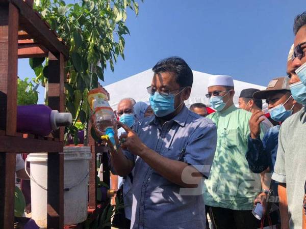 Che Abdullah melihat alat siram tanaman dari barangan terbuang yang direka oleh petani di kawasan bandar di Tumpat.