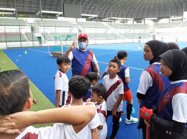 Megat D Shahriman ketika menyantuni pemain hoki cilik pada program berkenaan hari ini. - Foto Hockademy