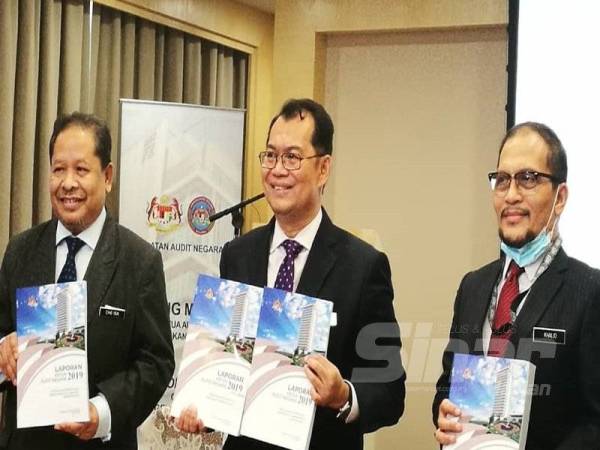 Nik Azman (tengah) menunjukkan buku Laporan Audit Negara Tahun 2019 pada sidang akhbar di Putrajaya hari ini.