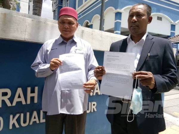 Mohd Zai (kanan) menunjukkan laporan polis yang dibuat di Ibu Pejabat Polis Daerah Dang Wangi, Kuala Lumpur hari ini.