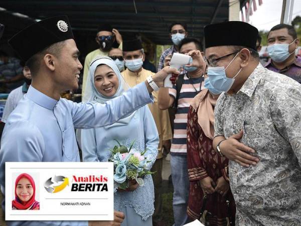 Pengantin lelaki, Muhammad Amirul Aizar Zawavi (kiri) melakukan saringan suhu badan kepada calon Bebas, Amir Khusyairi Mohamad Tanusi (kanan) sambil disaksikan oleh isterinya, Nurul Haziqah Mohd Asri (dua dari kiri) ketika menghadiri Majlis Perkahwinannya di Felda Besout 1 sempena kempen PRK DUN Slim di sini baru-baru ini. - Foto Bernama