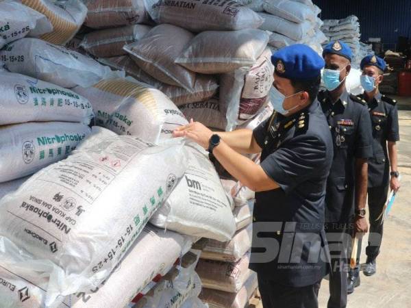 Mohd Shahran (kiri) memeriksa baja bersubsidi yang dirampas dalam serbuan di Jalan Datuk Kumbar, Alor Setar pada 18 Ogos lalu.