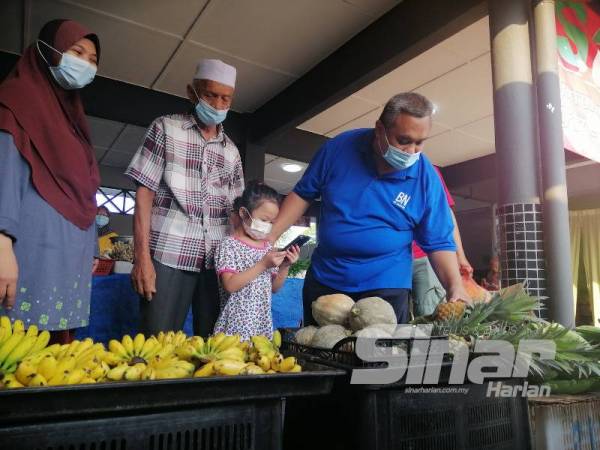 Aziz (dua dari kiri) bersama menantu dan cucu menemani Mohd Zaidi yang mengadakan lawatan ke Pasar Awam Slim River hari ini.