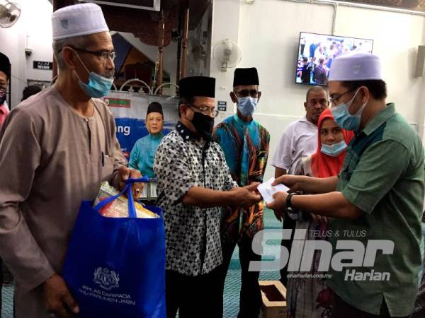 Ahmad (dua dari kiri) menyampaikan sumbangan kepada wakil penerima sempena program Prihatin Peladang Melaka di Masjid Sempang Kerayong dekat Rim semalam.