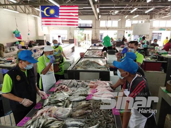 Norol Azali (kiri) meninjau operasi peniaga ikan di Pasar Sejahtera Ikan Segar Beserah di Kuantan hari ini.