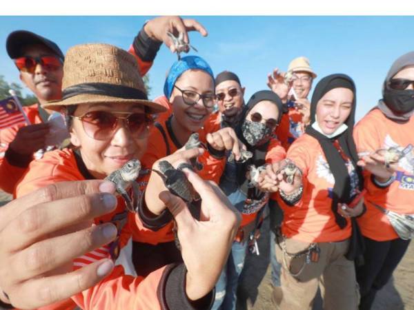 Yusaida (kiri) bersama ahli Kelab Penunggang Harley Davidson Muafakat Malaysia/Harley Davidson Riders Club Malaysia (HDRCM) melepaskan sebanyak 63 anak penyu sempena hari kebangsaan di Pantai Chendor.