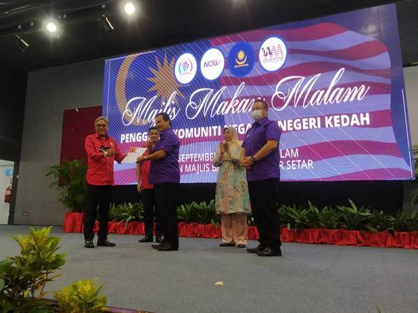 Azman (tengah) menyerahkan borang keahlian Bersatu kepada Suhaimi (kiri) sambil diperhatikan Azmin dan Zuraida pada Majlis Makan Malam Penggerak Komuniti Negeri Kedah di Dewan Majlis Bandaraya Alor Setar (MBAS), di sini, malam tadi.