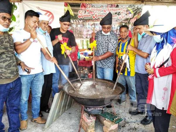 Afzal (empat dari kanan) bersama Razak (dua dari kanan) mengacau bubur asyura di Masjid As-Sobirrin hari ini.