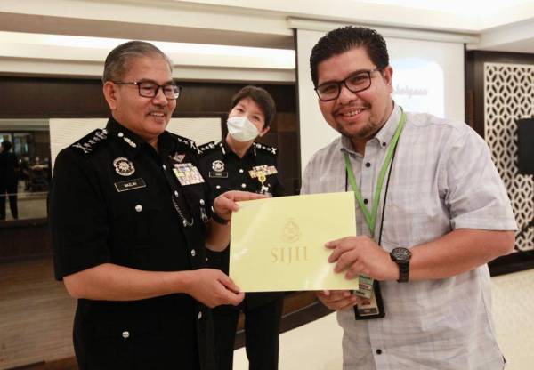 Salah seorang pengamal media menerima sijil penghargaan daripada Mazlan di Ibu Pejabat Polis Kuala Lumpur hari ini.