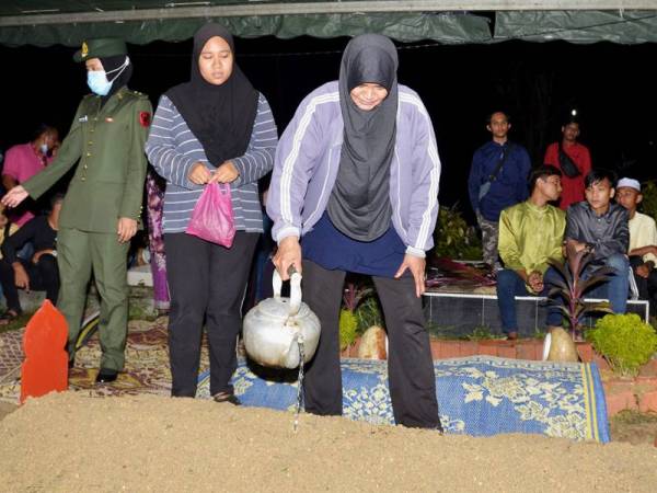 Rohana menyiram air di pusara anaknya selepas selesai upacara pengebumian di Tanah Perkuburan Islam Kampung Bakar Bata, Tanjung Rambutan hari ini.