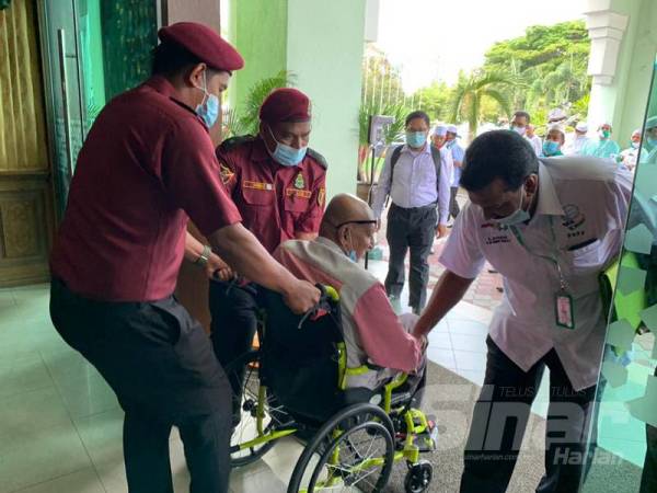 Anggota Jabatan Amal Malaysia membantu salah seorang hadirin yang menggunakan kerusi roda di Putik pagi ini.