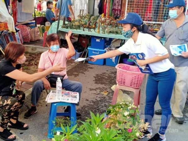 Kee Ying (kanan) menyampaikan risalah kempen kepada peniaga di Tamu Jalan Gaya pagi tadi.