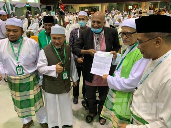 Murali (tengah) menyerahkan borang keahlian Pas kepada Abdul Hadi (dua dari kanan) selepas perbahasan sesi pertama pada Muktamar Tahunan Pas Kali Ke-66 di Pusat Tarbiah Islamiah Kelantan (Putik), Pengkalan Chepa hari ini.