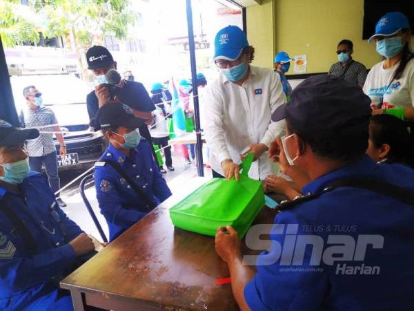 Christina menyampaikan poster kempen, pelitup muka dan cecair sanitasi kepada pengundi DUN Api-Api ketika membuat lawatan mesra di sekitar Jalan Gaya, Kota Kinabalu.