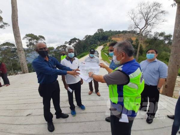 Rajendran (kiri) menunjukkan peta pelan kawasan bukit tersebut.