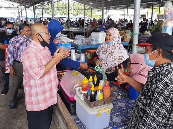 Mohd Fadzlee (kiri) bertanyakan khabar peniaga ketika melakukan tinjauan mesra di Tamu Pekan Menumbok kelmarin.