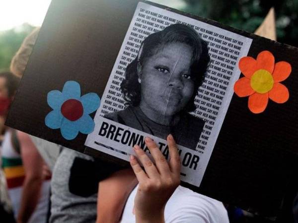 Gambar fail menunjukkan seorang penunjuk perasaan memegang poster mengandungi wajah Breonna Taylor yang ditembak mati oleh beberapa pegawai polis Louisville. - Foto AFP