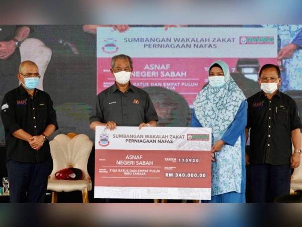 Muhyiddin (dua dari kiri) menyampaikan replika cek sumbangan wakalah zakat perniagaan NAFAS kepada wakil asnaf negeri Sabah di Beaufort.
