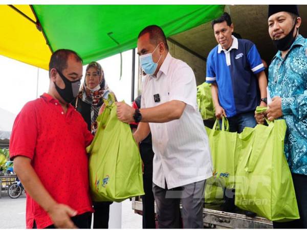 Ahmad Shukri (tiga dari kanan) menyerahkan sumbangan kepada seorang penerima di Surau Jumaat Al Hikmah, PPR Beringin semalam.