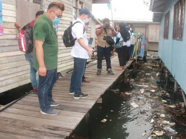 Edward (dua, kiri) ketika meninjau keadaan kawasan rumah atas air yang penuh dengan sampah ketika lawatan ke Pulau Gaya.