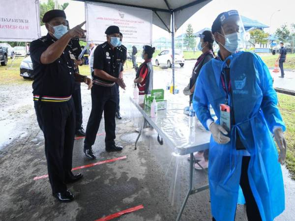 Hazani (kiri) ketika meninjau proses pengundian awal PRN Sabah di Mess Pegawai Kanan Ibu Pejabat Polis Kontinjen Sabah hari ini.- Foto Bernama