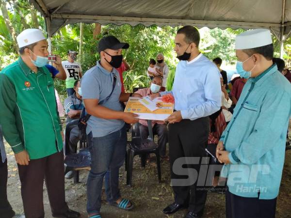 Mohammed Azman menyerahkan Faedah Pengurusan Mayat kepada Mohamad Haris (dua dari kiri) di Kampung Kuala Segantang Garam, Merbok semalam.
