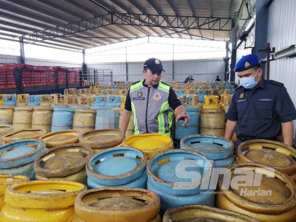 Aminuddin (kiri) menunjukkan antara rampasan tong gas LPG bersubsidi di sebuah stor haram di Jalan Sukepi, Kampung Jenjarom hari ini.