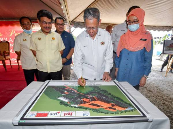 Mustapa (dua dari kanan) menandatangani plak pada Majlis Perasmian Tapak Projek Kolej Komuniti (KK) Jeli, di Bukit Bunga hari ini.