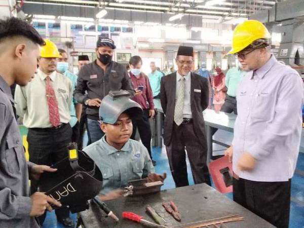 Razman (kanan) mendengar penerangan daripada seorang pelajar Kolej Vokasional Kerian sempena Program Bicara TVET di Kolej Vokasional Kerian, Bagan Serai semalam.