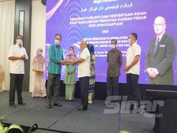 Mohd Anuar (dua dari kiri) menyerahkan Laporan Draf RTD Daerah Pekan 2035 kepada Rose Shamsul pada Majlis Perasmian Program Publisiti dan Penyertaan Awam Draf RTD Daerah Pekan di sini hari ini.