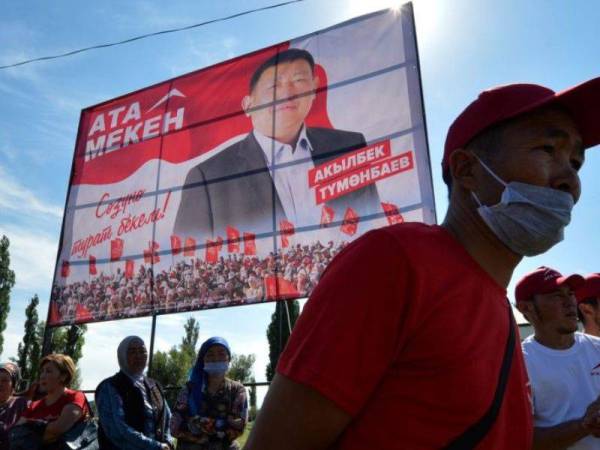 Beberapa orang berjalan dekat sebuah poster parti Ata-Meken di Kampung Ton pada 8 September lalu. - Foto AFP