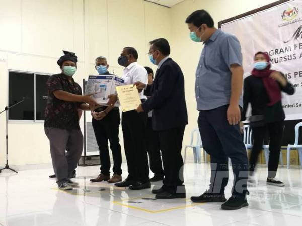 Saravanan (tengah) menyampaikan sijil dan mesin jahit kepada Shahruol Hadal Hadi, 35, pada Majlis Perasmian Penutupan Program Penjana Pembangunan Sumber Manusia Berhad (HRDF) B40 Kursus Asas Jahitan Pengenalan dan Kursus Penggunaan Mesin Jahit Tepi di Dewan Merdeka Tapah hari ini.