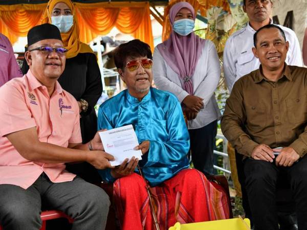 Pengerusi Perbadanan Kemajuan Filem Nasional Malaysia (FINAS) Zakaria Abdul Hamid (kiri) menyampaikan sumbangan kepada Raja Gelek Malaysia, Datuk M Daud Kilau, 82, (tengah) pada Program Ziarah Finas Prihatin di kediamannya di Kampung Sungai Balai Baruh hari ini. - Foto Bernama
