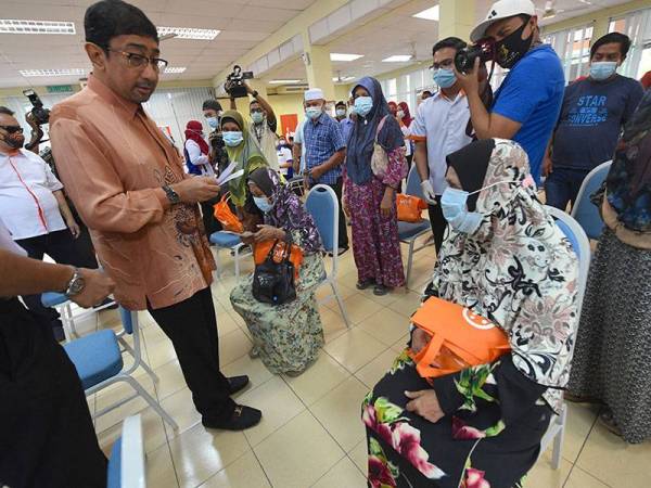 Zahidi (kiri) menyampaikan sumbangan zakat kepada golongan asnaf selepas merasmikan Program Usahawan Digital Bersama TM di Alor Tampang, Beseri hari ini. - Foto Bernama