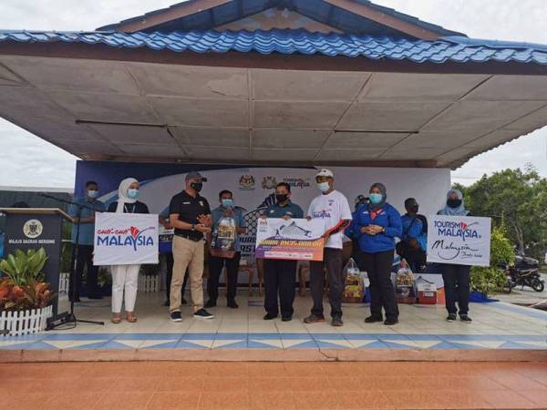 Asman (dua dari kiri) dan Ammar (tengah) menyerahkan replika cek kepada pemenang selepas program Tourism Malaysia Surfcasting Tour 2020 do Dataran Mersing, Mersing hari ini.