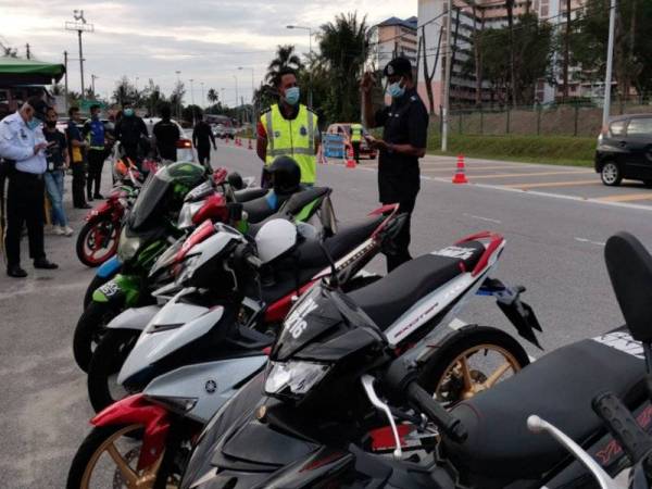 Nor Omar (dua dari kanan) memeriksa motosikal yang disita setelah diubah suai tidak mengikut spesifikasi dalam operasi Bersepadu Samseng Jalanan di KM6 Jalan Lumut semalam.