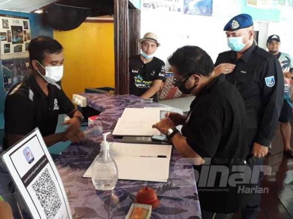 Ammar (kanan) melihat buku pendaftaran semasa melakukan pemeriksaan dan pematuhan SOP di Twin Beach Resort, Pulau Sibu, Mersing hari ini.