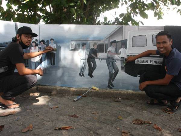 Mohamad Azizul (kanan) dan rakannya, Mohd Hisbullah menunjukkan lukisan mural tragedi feri karam di Sungai Kerian pada 13 September 1972 di tembok setinggi lima kaki di Taman Pinggiran Sungai Kerian. - Foto Bernama