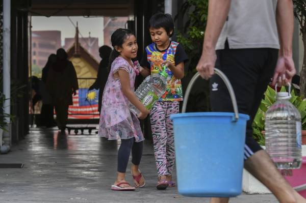 Kanak-kanak turut sama mengangkut air bersih berikutan gangguan bekalan air yang berlaku selepas Sungai Semenyih mengalami pencemaran ketika tinjauan di Kuarters Kakitangan Kerajaan Presint 16 semalam. Foto Bernama