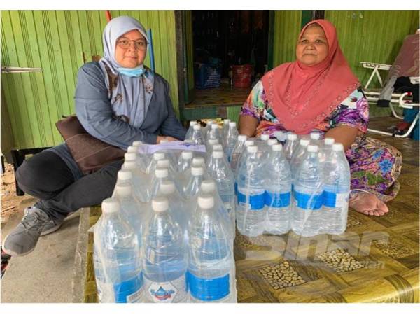 Nik Munirah Akmal (kiri) menghantar air minuman kepada Khabsah di rumahnya di Kampung Tok Puchong, Kedai Buloh hari ini.