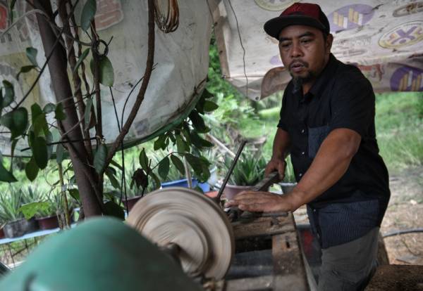 Melarik kayu untuk membuat bingkai rebana ketika proses menghasilkan rebana. -Foto Bernama