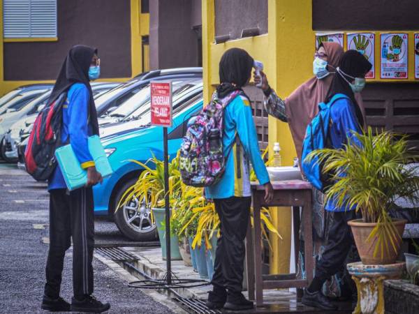 Guru sekolah mengimbas suhu badan murid di Sekolah Kebangsaan Permatang Janggus, Penaga hari ini. - Foto Bernama