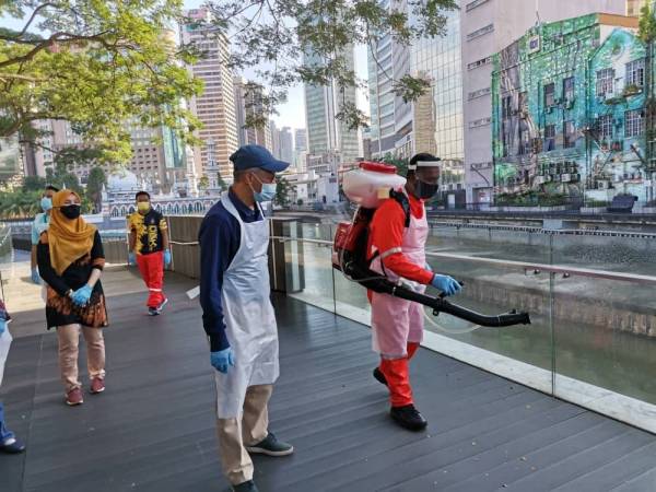 Mahadi (kiri) meninjau sanitasi awam yang dilakukan sekitar Dataran Merdeka hari ini.