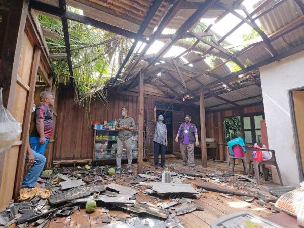 Ridzuan (dua kanan) meninjau rumah Kamaruddin yang rosak ditimpa pokok tumbang dalam kejadian ribut malam tadi.