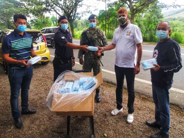 Jasvir Singh (dua dari kanan) menyerahkan sumbangan pelitup muka kepada petugas di sekatan jalan raya Benus dan sekatan jalan raya Jalan Lama Kuala Lumpur-Bentong semalam.