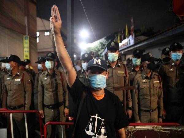 Seorang penunjuk perasaan prodemokrasi menunjukkan simbol hormat tiga jari ketika perhimpunan di luar balai polis Nonthaburi di pinggir Bangkok semalam. - Foto AFP